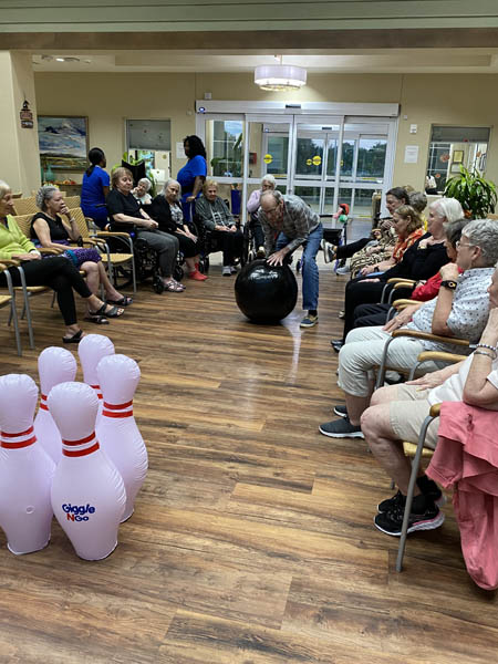 memory care resident pushing the bowling ball