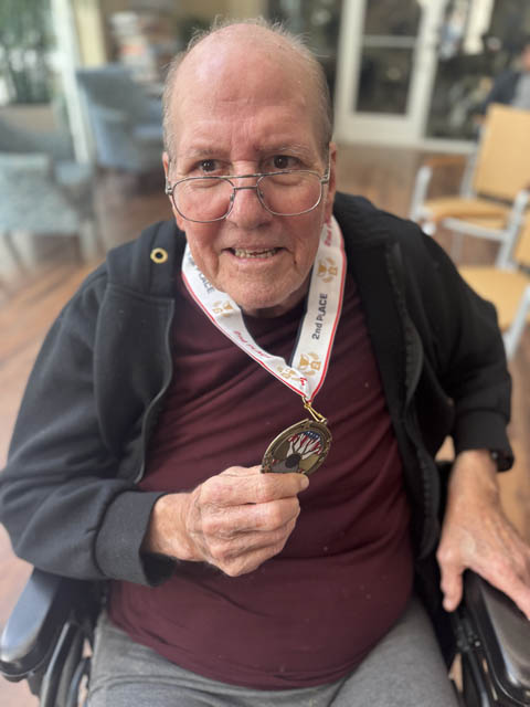 memory care resident showing off his medal